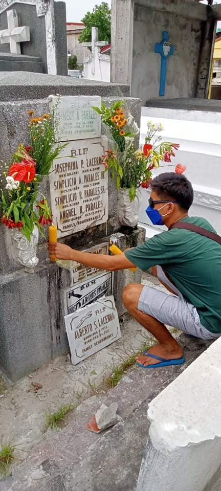A photo for my September San Diego Taphophile update-a family member placing flowers and candles on the family tomb during Undas in the Philippines
