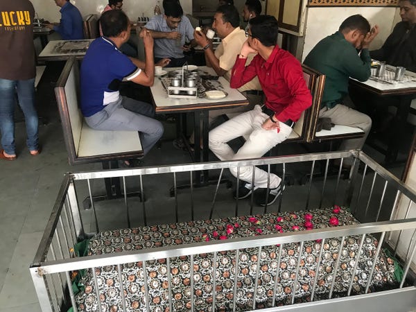 View of diners at a table, sitting next to a grave
Eat Among the Graves in this Restaurant in India